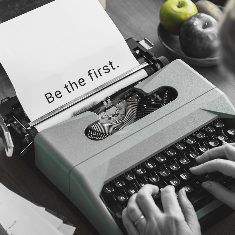 Typewriter with the text 'be the first.'